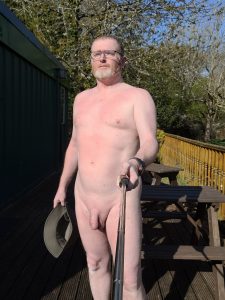 Naked man taking a selfie outdoors on a sunny day.