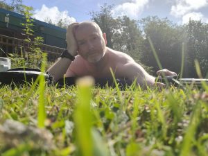 Man lying on grass outdoors, relaxing in a sunny garden setting.